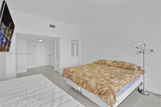 bedroom with tile patterned floors, ornamental molding, and a closet