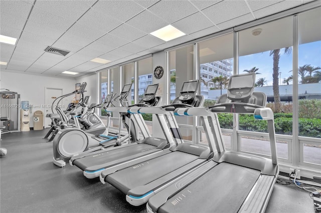 gym with a wall of windows and a drop ceiling