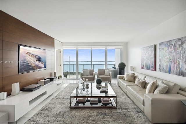 living room featuring a water view, expansive windows, and wood walls