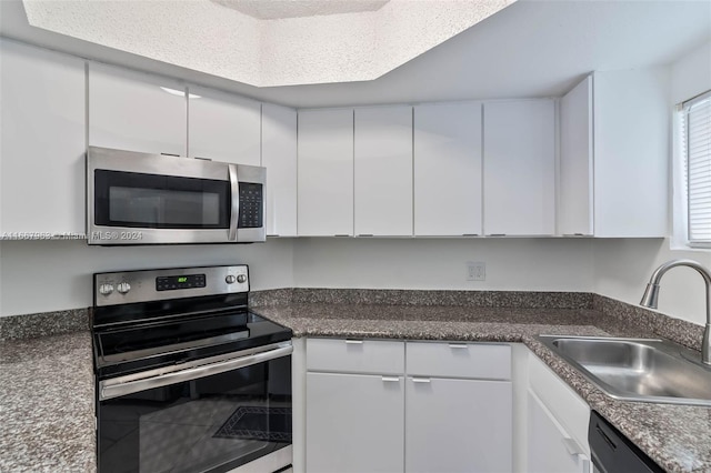 kitchen with white cabinets, sink, stainless steel appliances, and a textured ceiling