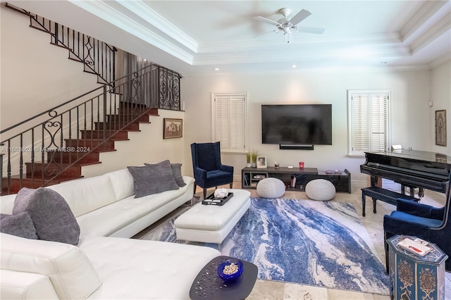 living room with ceiling fan, a raised ceiling, and crown molding