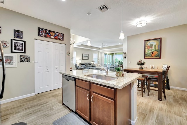 kitchen featuring dishwasher, sink, an island with sink, light hardwood / wood-style floors, and decorative light fixtures