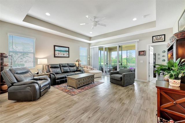 living room featuring a raised ceiling and ceiling fan