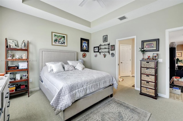 carpeted bedroom featuring a tray ceiling and ceiling fan