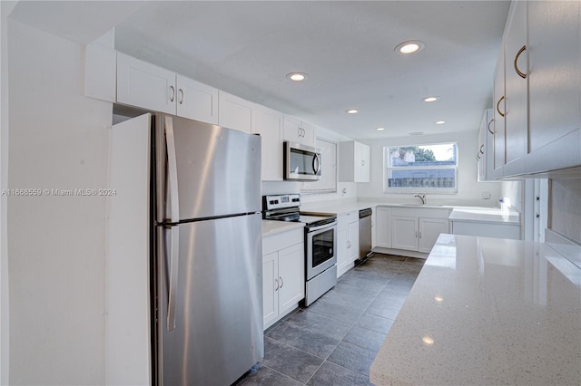 kitchen with sink, light stone counters, white cabinetry, and stainless steel appliances