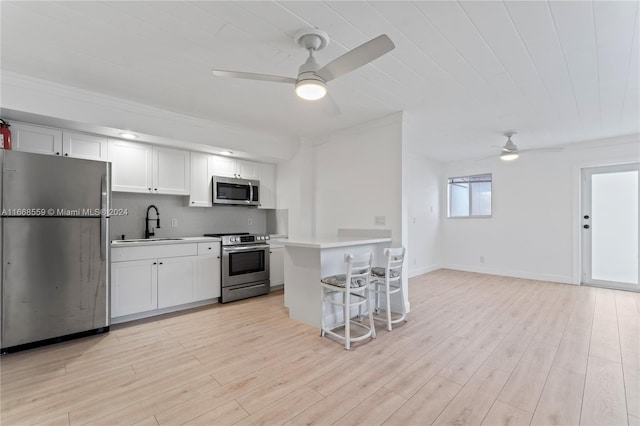 kitchen featuring white cabinets, a kitchen breakfast bar, light wood-type flooring, and stainless steel appliances