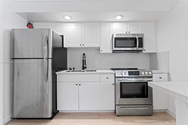 kitchen with backsplash, sink, white cabinetry, and stainless steel appliances