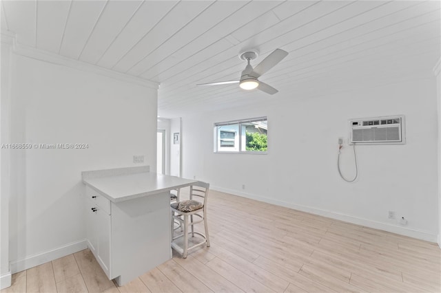 kitchen with a kitchen bar, kitchen peninsula, light hardwood / wood-style floors, and a wall mounted air conditioner