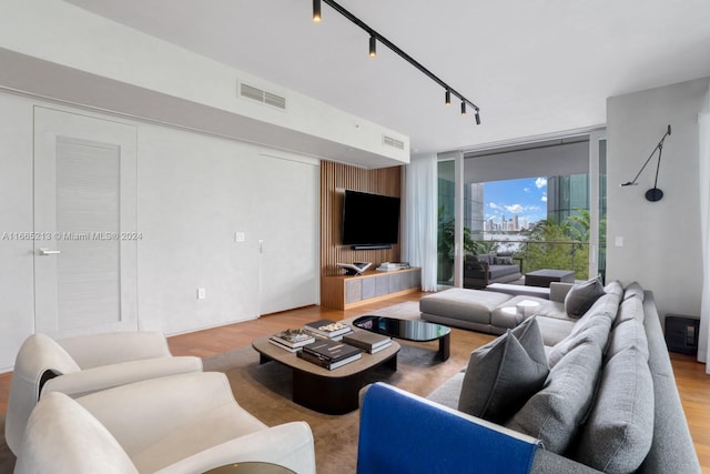 living room with a wall of windows and light wood-type flooring