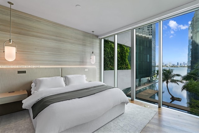 bedroom with access to exterior, expansive windows, and light wood-type flooring