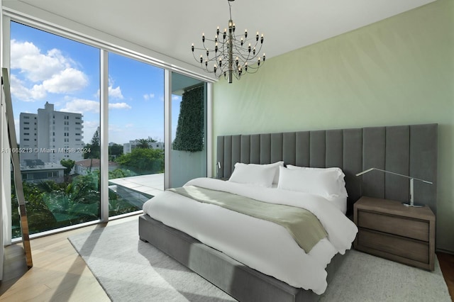 bedroom featuring access to exterior, light hardwood / wood-style floors, and a notable chandelier