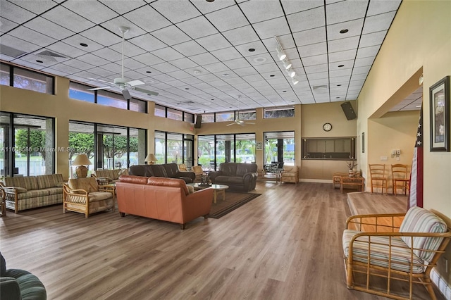 living room with a healthy amount of sunlight, a towering ceiling, ceiling fan, and hardwood / wood-style flooring