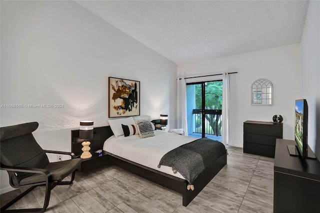 bedroom featuring a textured ceiling, lofted ceiling, and access to exterior