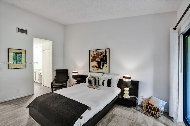 bedroom featuring a textured ceiling, connected bathroom, and hardwood / wood-style flooring