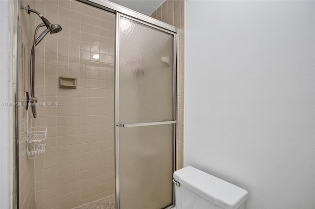 bathroom featuring a shower with door and toilet