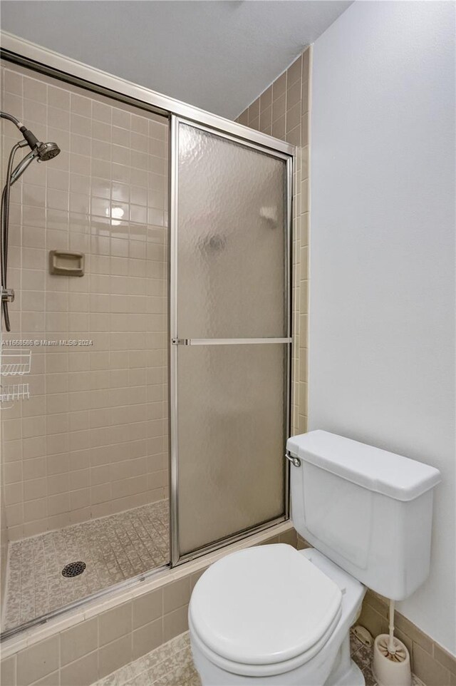 bathroom featuring walk in shower, tile patterned flooring, and toilet