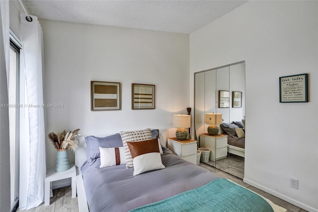 bedroom featuring light hardwood / wood-style floors, a closet, and a textured ceiling