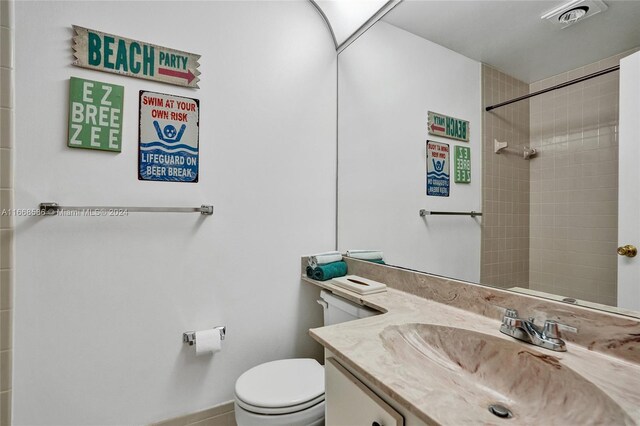 bathroom featuring tiled shower, vanity, and toilet