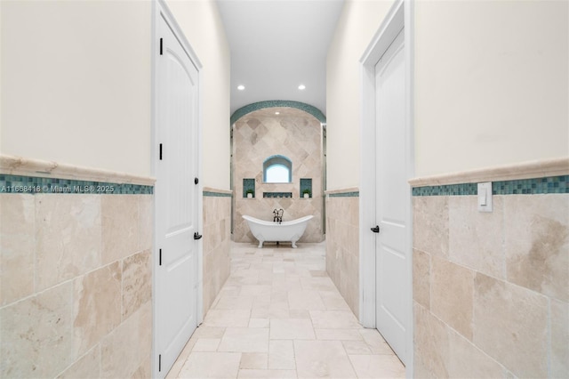 bathroom featuring a bath and tile walls