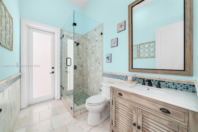 bathroom with tile patterned floors, vanity, tile walls, toilet, and a shower with shower door