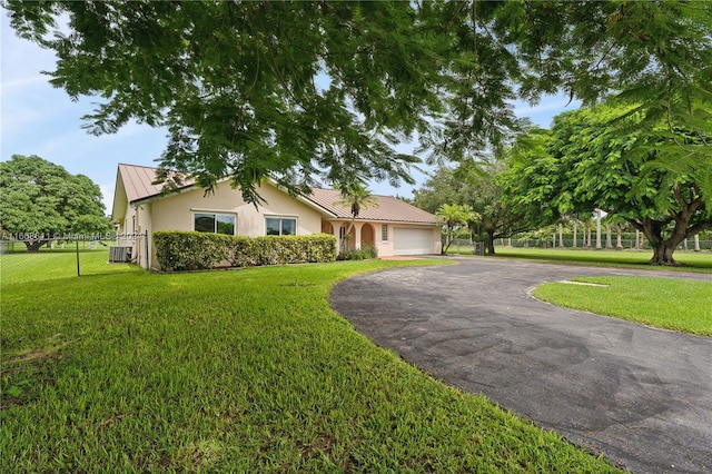 ranch-style home with cooling unit, a front yard, and a garage