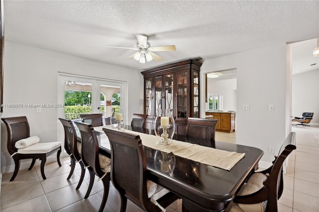 tiled dining space with ceiling fan, a textured ceiling, and french doors