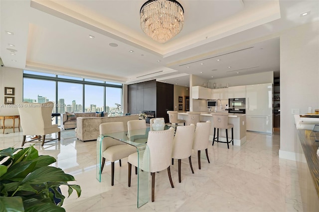 dining space featuring a notable chandelier, a tray ceiling, and a wall of windows