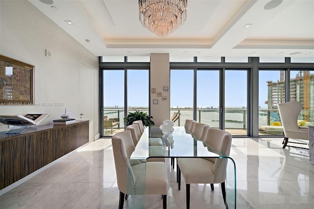 dining space featuring floor to ceiling windows, a water view, plenty of natural light, and a tray ceiling