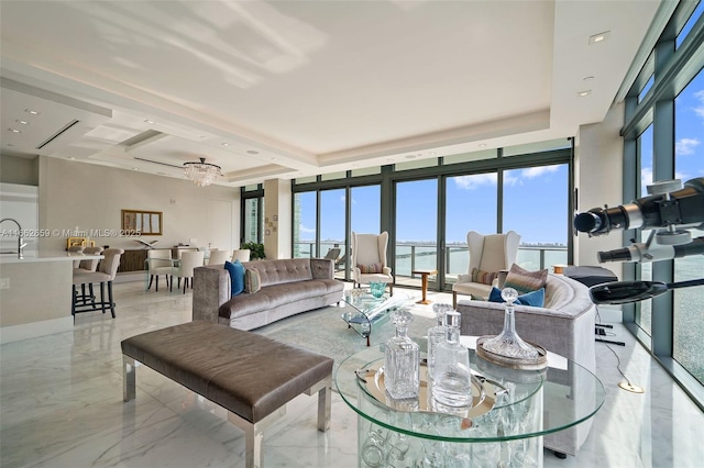 living room with expansive windows, a water view, sink, and an inviting chandelier