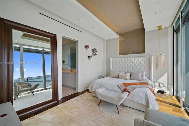 bedroom with hardwood / wood-style flooring, ensuite bath, and access to outside