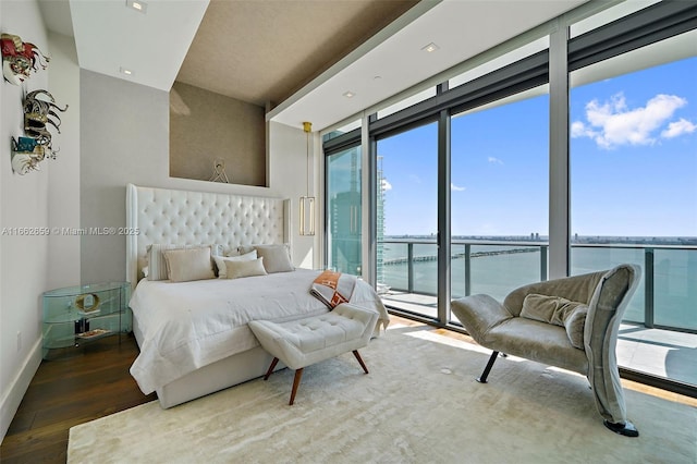 bedroom featuring multiple windows, a water view, access to exterior, and dark hardwood / wood-style flooring