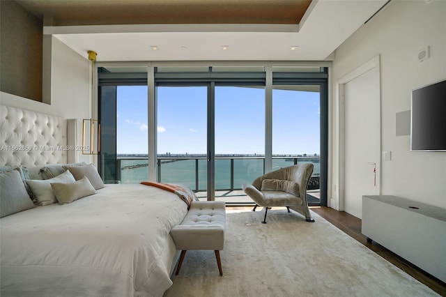 bedroom featuring a wall of windows, wood-type flooring, and a water view