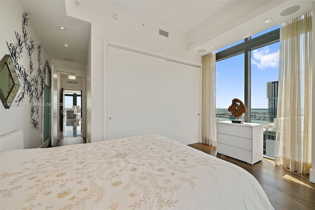 bedroom featuring multiple windows, a water view, and dark wood-type flooring