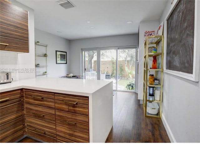 kitchen featuring backsplash, dark hardwood / wood-style floors, and kitchen peninsula