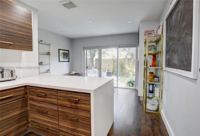 kitchen featuring kitchen peninsula, dark hardwood / wood-style floors, and backsplash