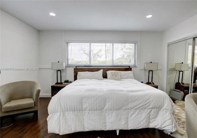 bedroom with a closet, dark wood-type flooring, and multiple windows