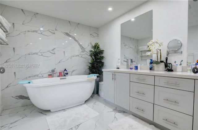 bathroom with vanity, a tub to relax in, and tile walls