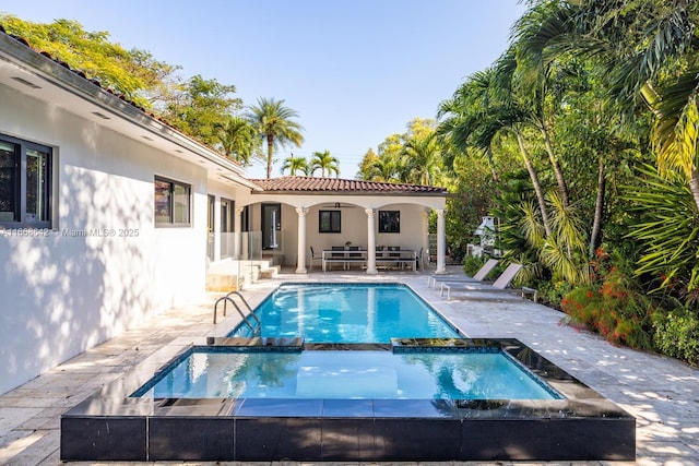 view of pool with an in ground hot tub, an outdoor hangout area, and a patio area