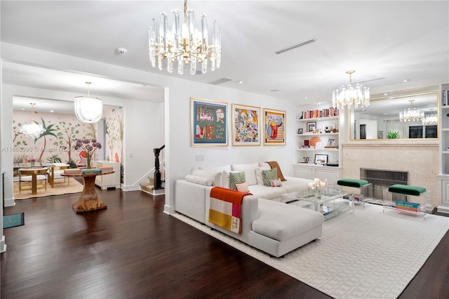 living room featuring visible vents, dark wood-type flooring, stairway, a premium fireplace, and a notable chandelier