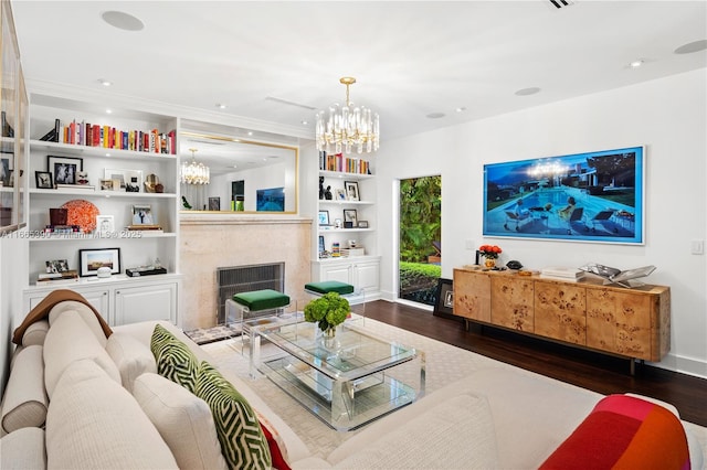 living area with dark wood finished floors, built in features, recessed lighting, a fireplace, and a notable chandelier