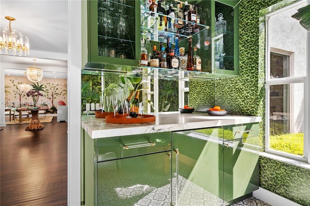 bar featuring tasteful backsplash, a notable chandelier, and wood finished floors