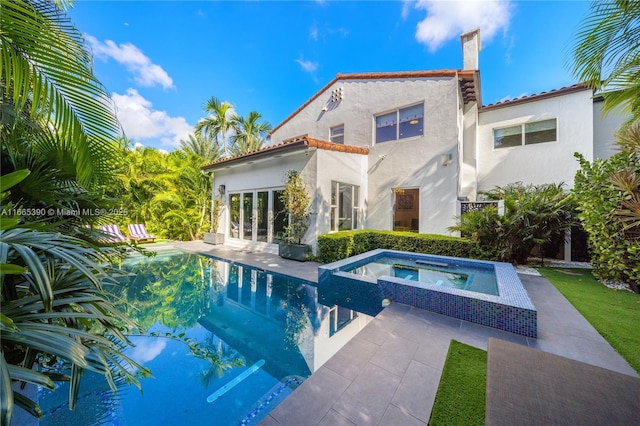 rear view of property with a patio, an in ground hot tub, an outdoor pool, stucco siding, and french doors