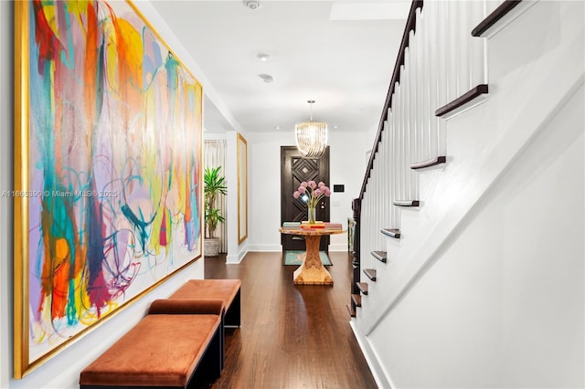 corridor with a notable chandelier, stairs, baseboards, and dark wood-style flooring