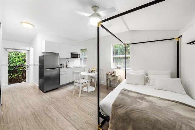 bedroom featuring ceiling fan, lofted ceiling, freestanding refrigerator, a wall mounted AC, and a sink