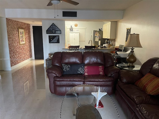 living room with ceiling fan, brick wall, and sink