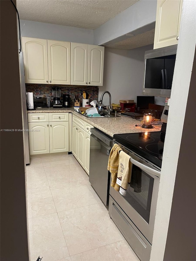 kitchen with sink, light stone countertops, stainless steel appliances, and tasteful backsplash