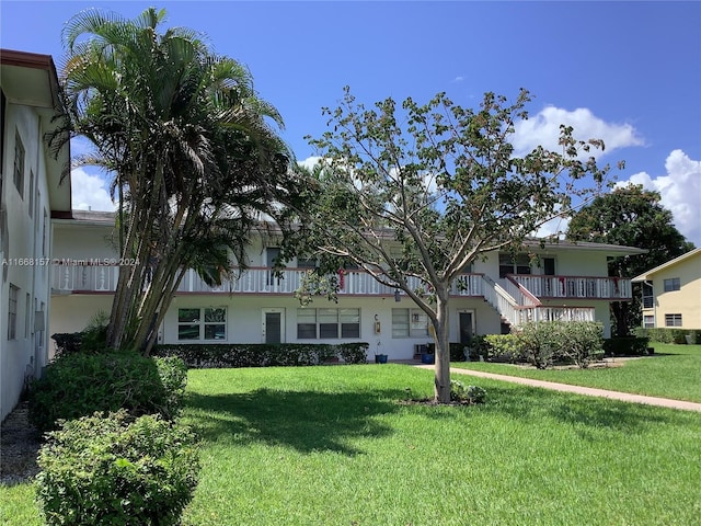 view of front of home with a balcony and a front yard