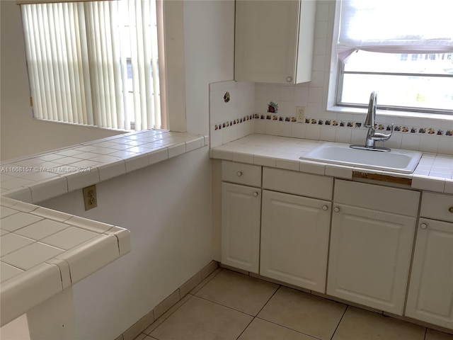 kitchen with white cabinets, backsplash, tile counters, and sink