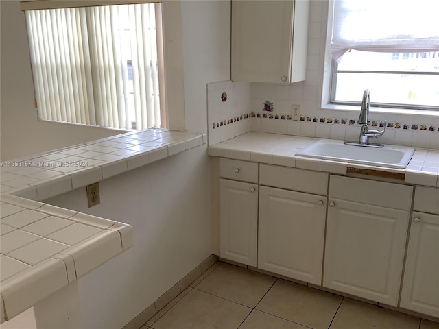 kitchen featuring white cabinetry, tile counters, and sink