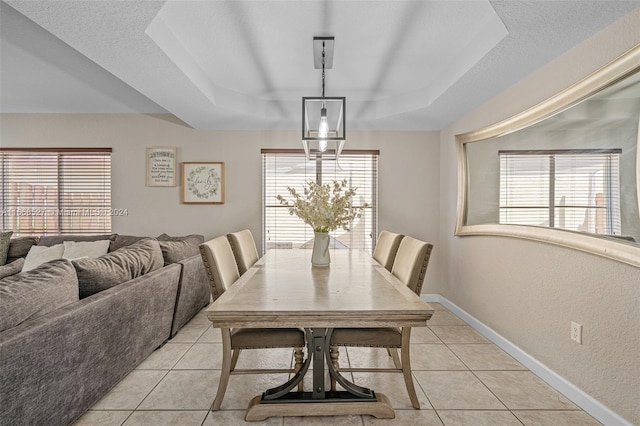 dining room featuring a textured ceiling, a raised ceiling, and light tile patterned floors